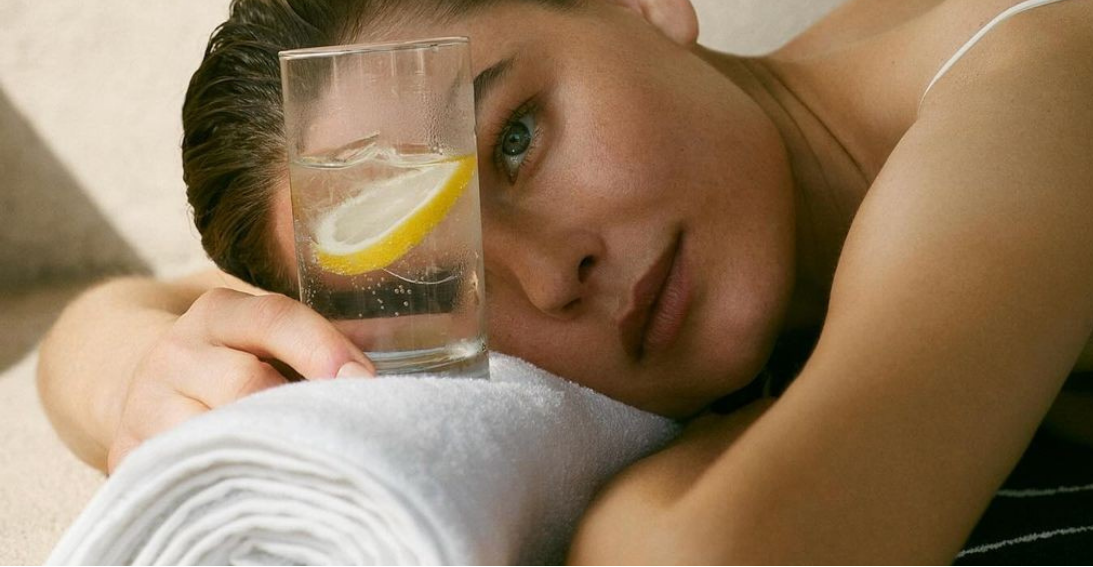 Woman resting beside a glass of lemon water